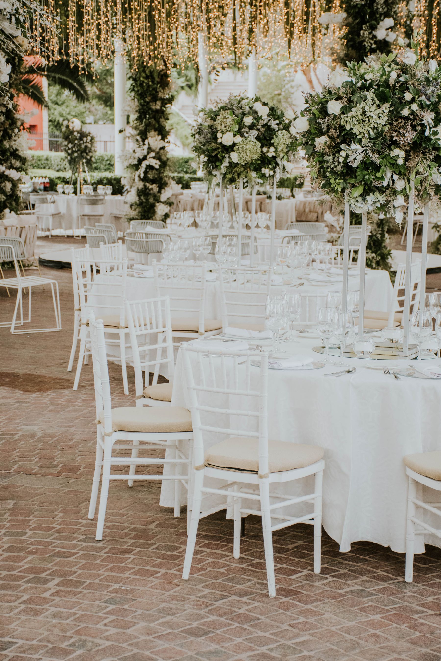 Montaje de boda campestre al atardecer con mesas vestidas de blanco y luces colgantes